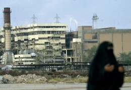 A woman walks past a Basra Electricity Company power plant that has seen better days. A woman walks past a Basra Electricity Company power plant that has seen better days.